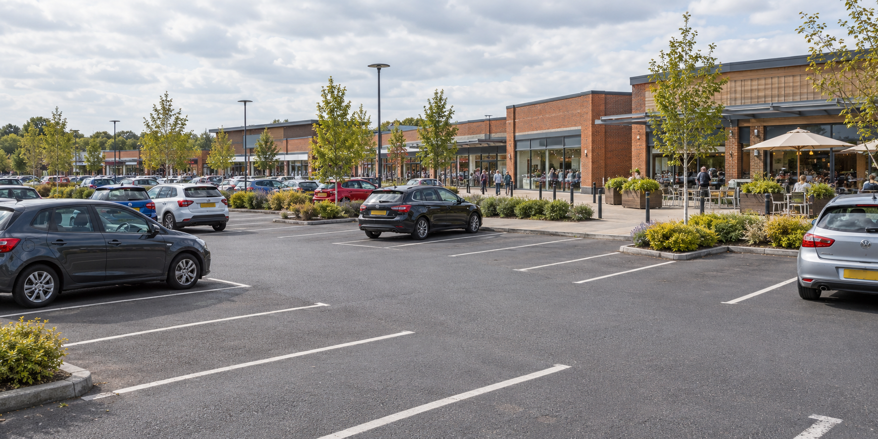 Illustrative UK outdoor shopping centre with marked parking spaces and parked cars